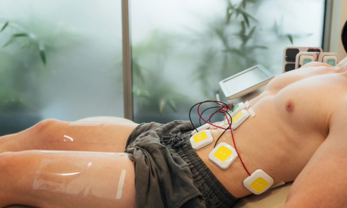 Choose the Right Body Contour Clinic and Treatment: 3 Things That Matter Most 5 Patient lying with electrode pads on abdomen during body contour clinic and treatments for non invasive muscle stimulation.