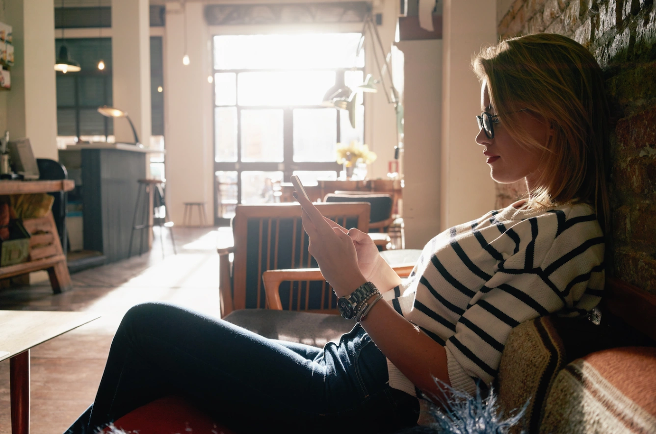 Woman relaxing on a couch using her phone, reflecting everyday wellness habits supported by an nmn supplement.