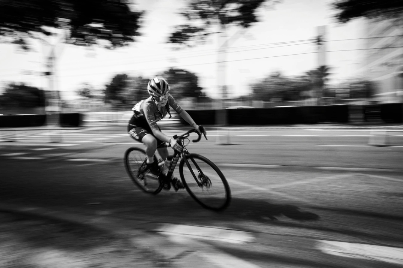 Cyclist racing on a road in motion blur, symbolising endurance and performance supported by an nmn supplement.