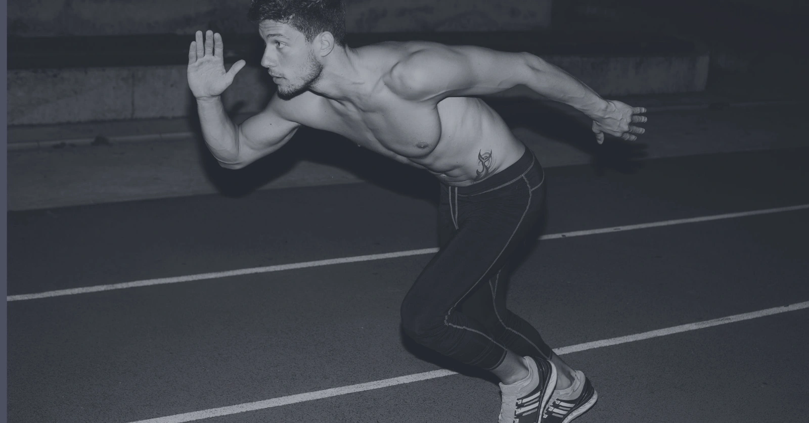 Male athlete sprinting on a track in a powerful start pose connected to performance and niacin vs nmn.