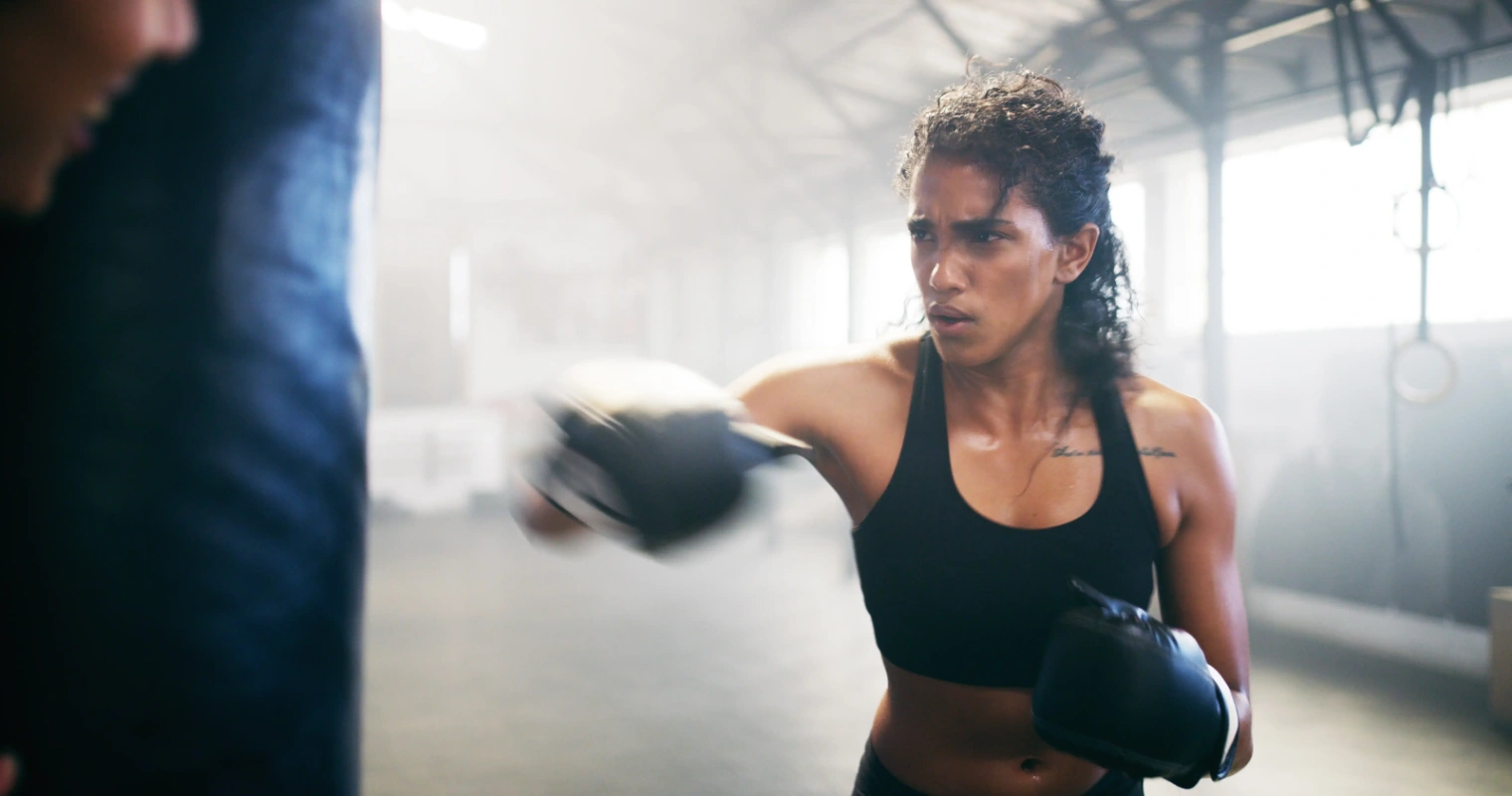 Focused woman punching a heavy bag during boxing workout while exploring fitness and niacin vs nmn benefits.