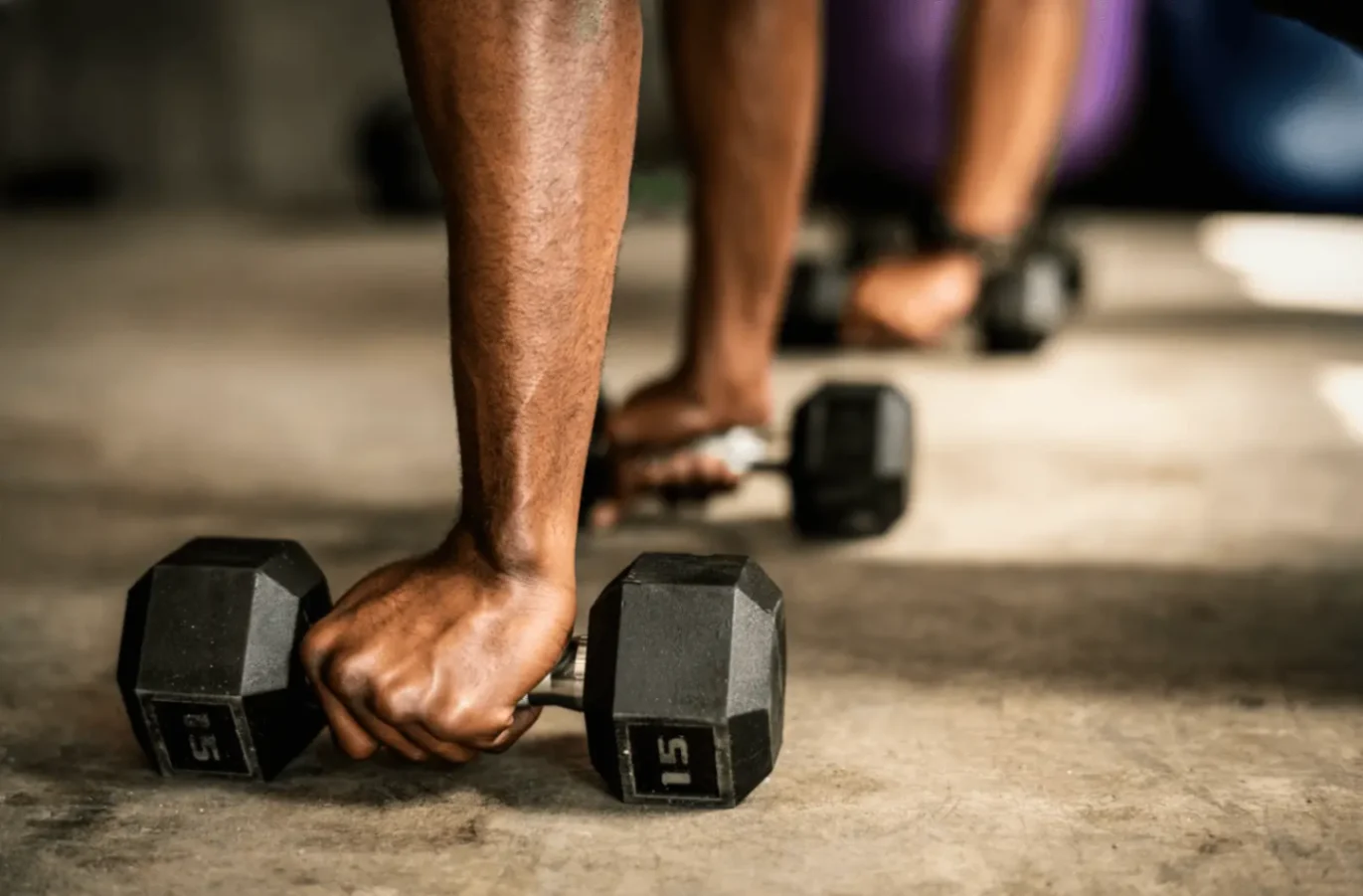 Close up of a hand lifting a dumbbell on the floor during strength training linked to niacin vs nmn.