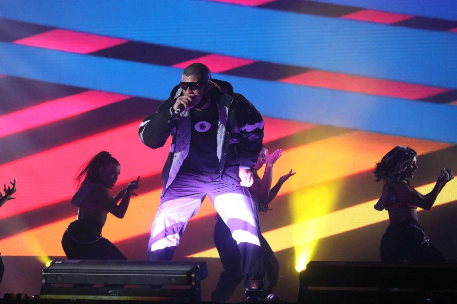 Singer performs on stage with dancers and colourful lights during a Bad Bunny Grammy performance.