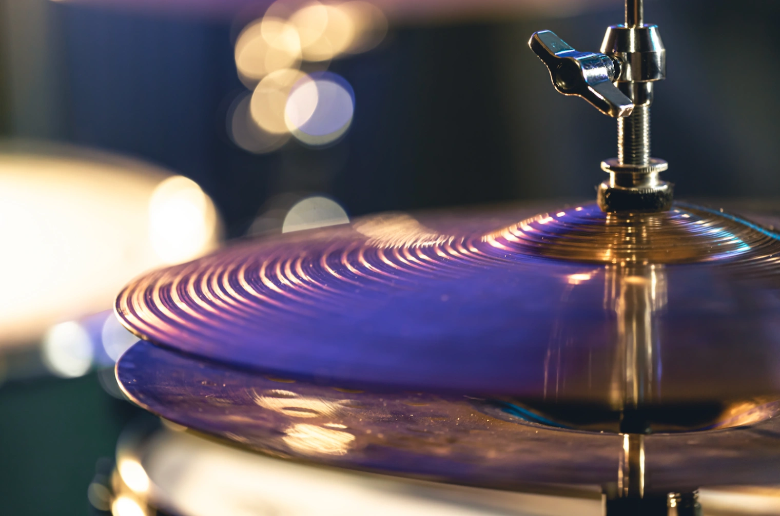 Close up of a shining drum cymbal vibrating under stage lights at a Bad Bunny Grammy show.
