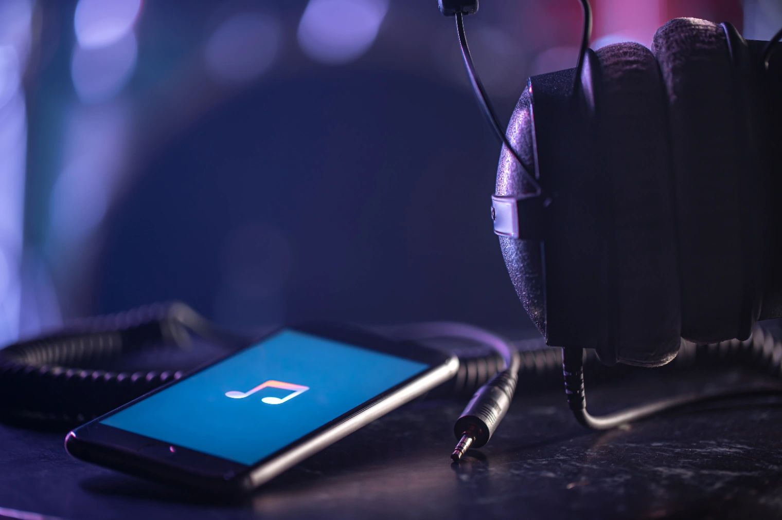 Headphones beside a phone playing music, reflecting a Bad Bunny Grammy listening experience.