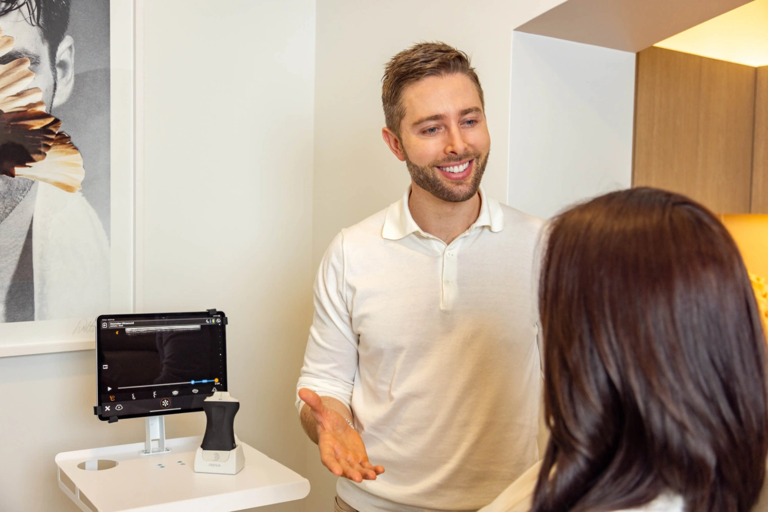 Clinician consulting patient beside device during ultrasound guided aesthetics to plan safe and targeted cosmetic treatment. 